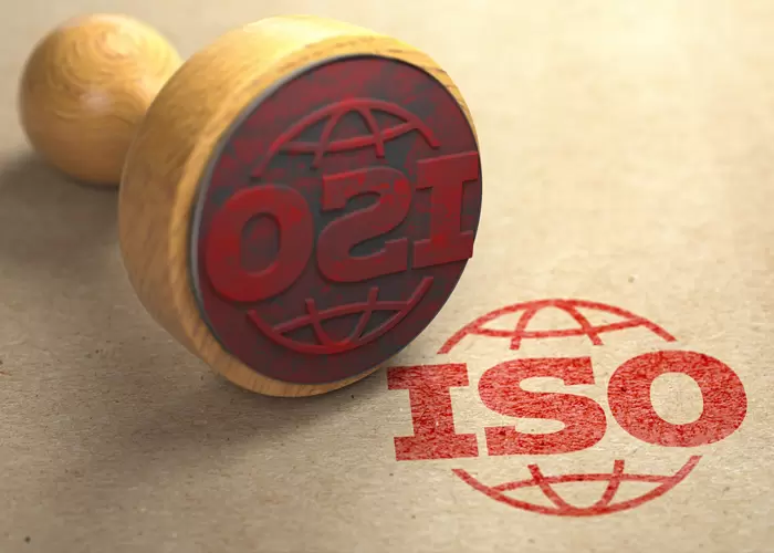Close-up image of a wooden stamp with red ISO text and globe symbol, stamped on paper
